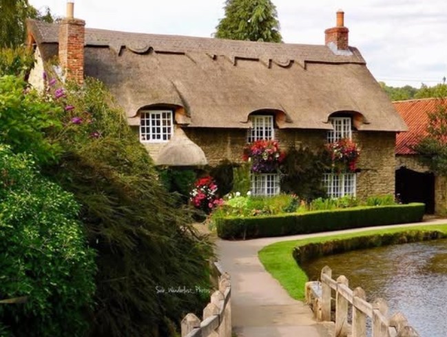Beck Isle Cottage, the 17th-century thatched cottage beside Thornton Beck in Thornton-le-Dale, with flowers in the front garden